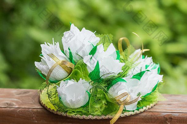 纸白色的花，用纸制成。绿色背景的木桌上摆放着一束纸花。手工艺术。爱好概念