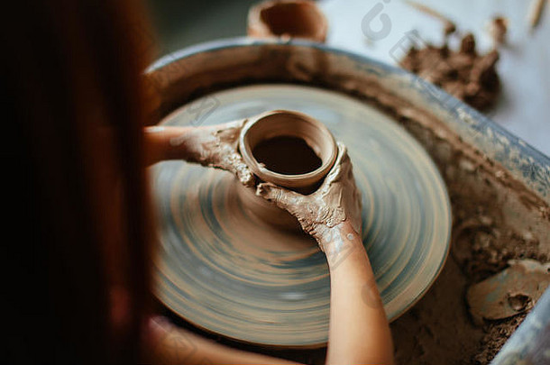 女陶工在工作室的投掷轮上工作。粘土作坊