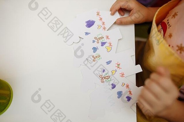 在隔离期间，一个在家接受训练的孩子用纸做折纸。儿童的创造力。双手合拢