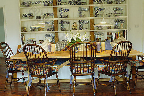 乡村餐厅的古董温莎椅和简单的松木桌子，白色架子上有蓝 白瓷器架