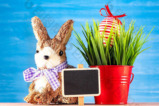 复活节彩蛋和可爱的兔子在绿草的木桌上。节日装饰