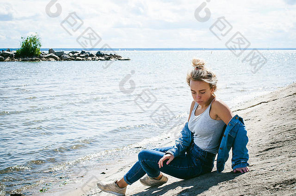 年轻漂亮的女人在户外穿着牛仔裤。一个脸上有雀斑的女孩的肖像，海滩上的时尚女孩，在一个阳光明媚的夏秋日