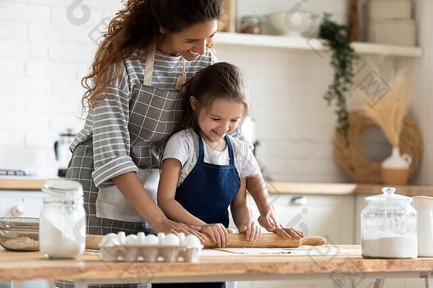 年轻的妈妈和小女儿一起在厨房烤面包