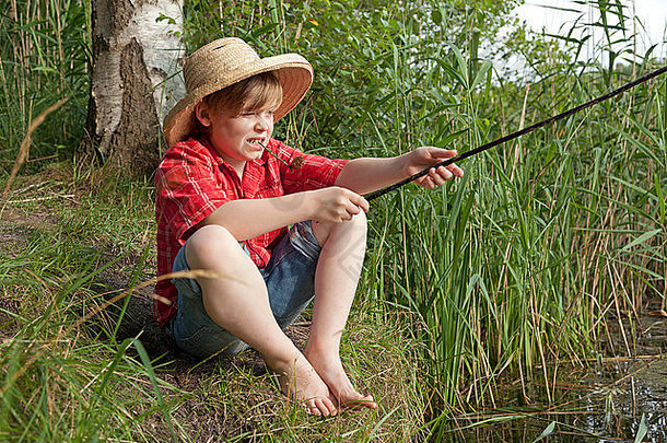 年轻的男孩穿着《哈克贝利·费恩找到钓鱼