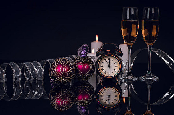 两个酒杯，配香槟、时钟和圣诞装饰品，黑色背景，反光。空间。圣诞快乐，新年快乐，