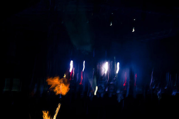运动模糊的夜景，展示了一个食火魔术师的手电筒。背景暗而模糊，只有火焰清晰可见。