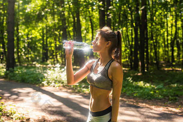 年轻女子在户外跑步后喝水