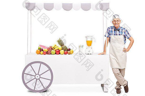 站在一个摊位旁边的高级苏打混蛋，摊位上有一个榨汁机和一堆新鲜水果，背景是白色的