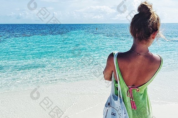 马尔代夫岛上，一个女孩在白色沙滩上看着两种颜色的大海