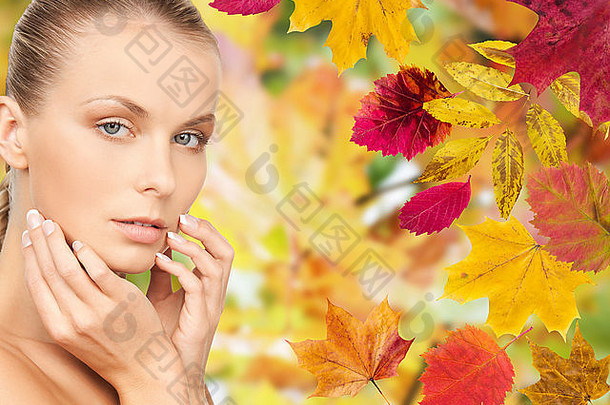 美丽的女人在秋天抚摸着她的脸