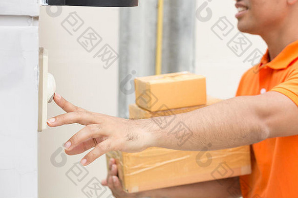 拿着包裹盒的亚裔男子按响了顾客的门铃。身着橙色制服的送货员按铃。速递服务及送货服务