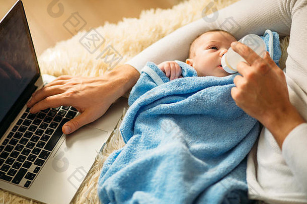 男人一边躺在床上一边用笔记本电脑喂养小宝宝