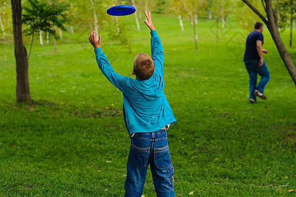 小男孩在绿草上玩飞盘
