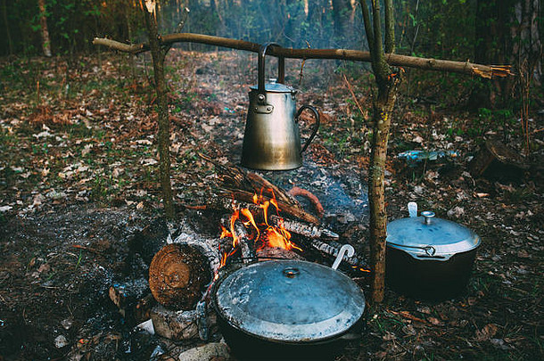 古老的复古铁制营地水壶和平底锅在森林里的火上<strong>烧</strong>水。明亮的火焰，黄昏的篝火。
