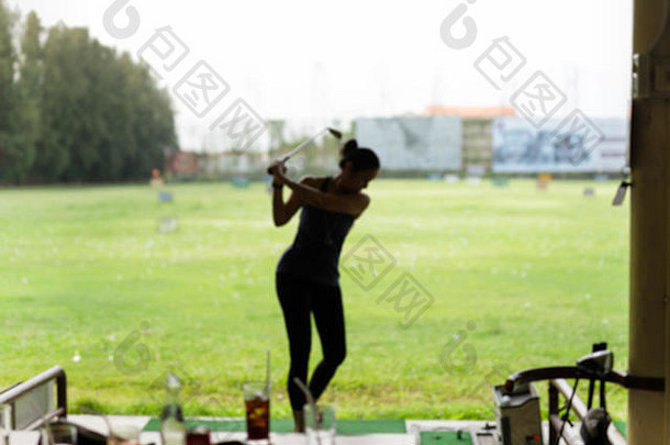 一个在高尔夫练习场练习挥杆的女人。
