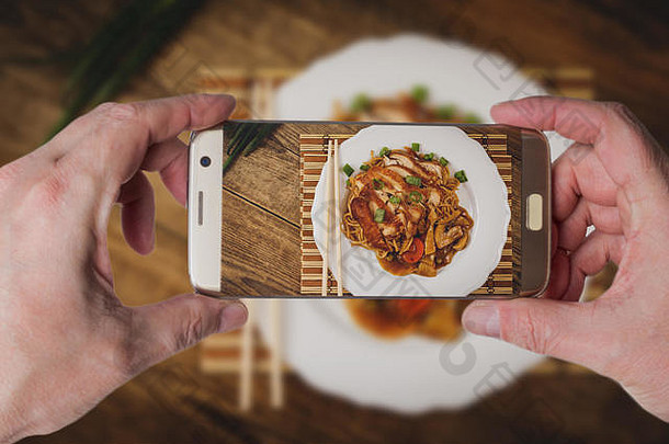 男子拍摄中国面条配炸鸡肉和蔬菜的照片
