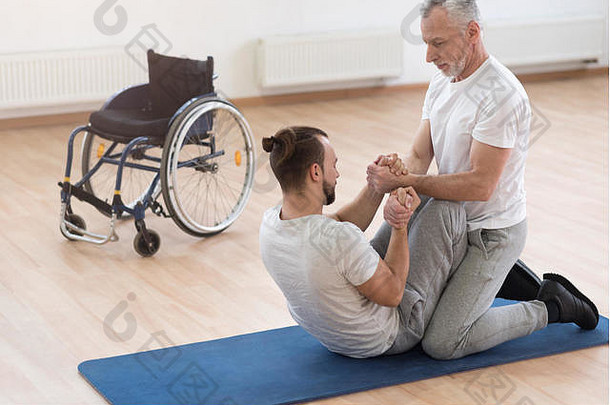 熟练的骨科医生在健身房帮助残疾人