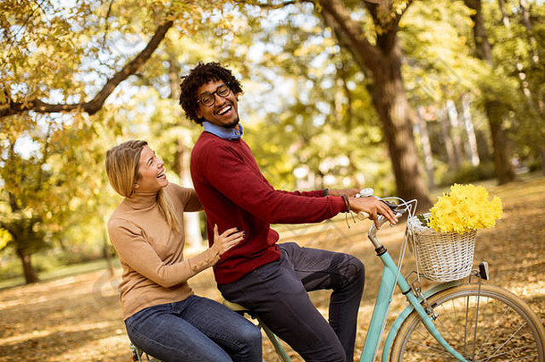 在秋季公园骑自行车的多种族年轻夫妇
