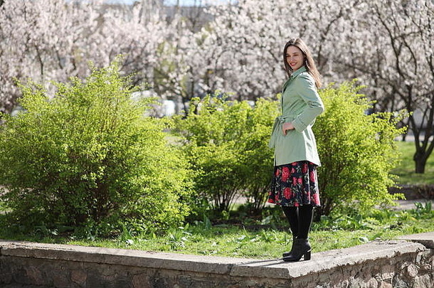 年轻的女人摆姿势绿色灌木开花杏背景