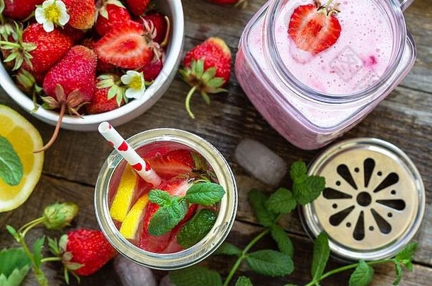 健康饮食观念。柠檬水配新鲜草莓和草莓水果酸奶冰沙或牛奶奶昔，放在一张质朴的木桌上。俯视平面图l