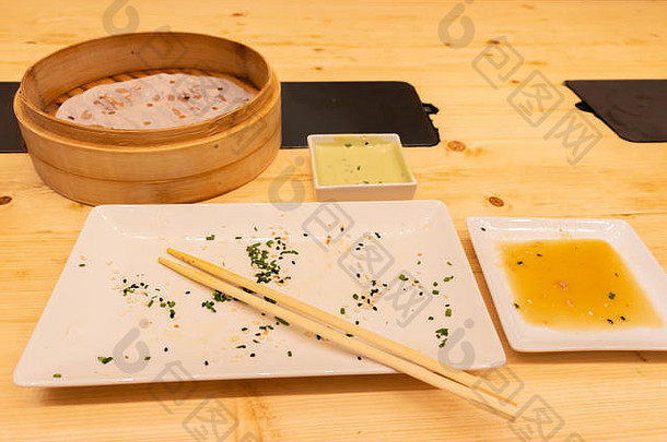 在亚洲餐厅或包饺子的中<strong>国酒</strong>吧里，用筷子在木桌上用蒸饺做成的空盘子和木制蒸笼。