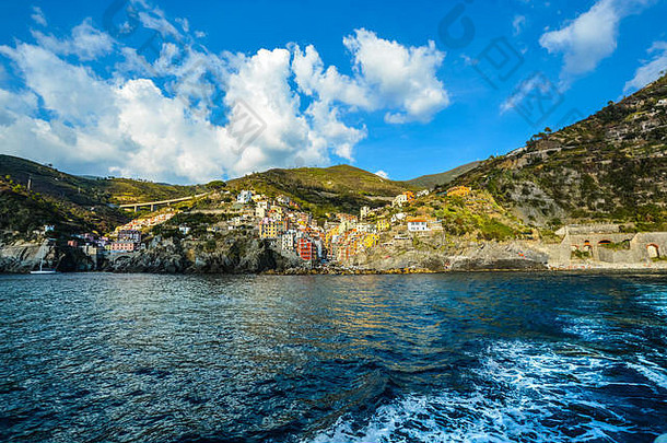 意大利利古里亚海岸Riomaggiore五颜六色的Cinque Terre村，在夏末一个多云的日子里从一艘游轮上拍摄