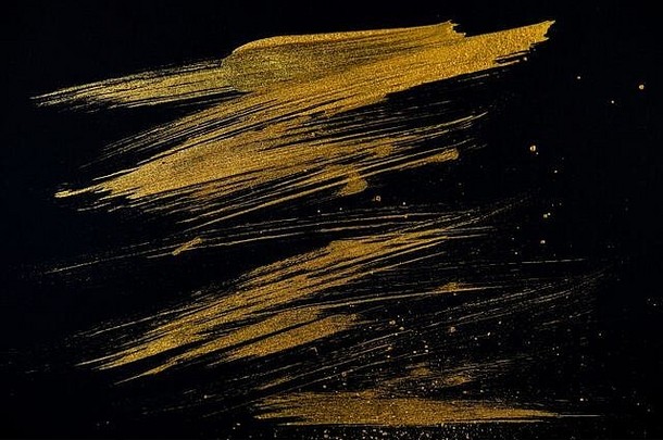 用金色画笔在黑纸上画画。抽象背景。