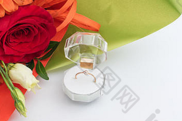 订婚戒指装在一个礼品盒里，盒子里有一束鲜艳的鲜花。结婚的提议。情人节礼物。为心爱的沃求婚