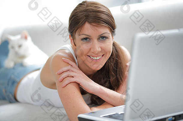 在家和白猫在笔记本电脑上工作的年轻女子。MR-01-24-09；PR-01-24-09