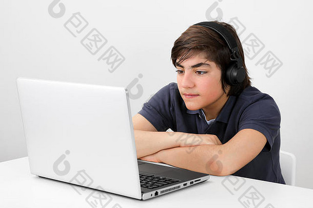 高加索人十几岁的男孩耳机坐着<strong>表</strong>格看视频移动PC屏幕