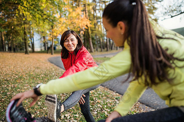 女跑步者伸展运动腿在户外公园秋天自然