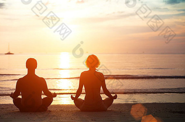 年轻的夫妇莲花位置冥想海滩日落