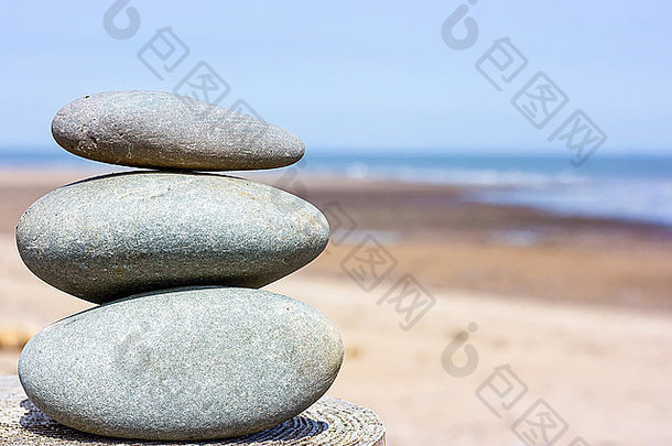 堆放石头坐着木帖子海滩蓝色的天空沙子海