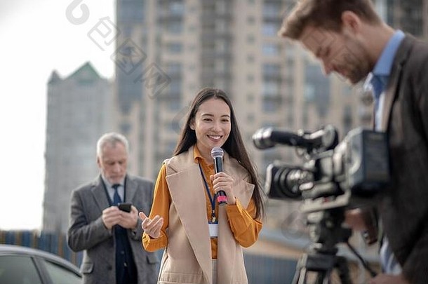 年轻的可爱的女记者会说话的摄像机
