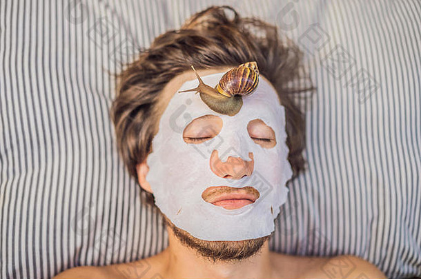 年轻的男人。使脸面具蜗牛粘液蜗牛爬行脸面具水疗中心男人。水疗中心
