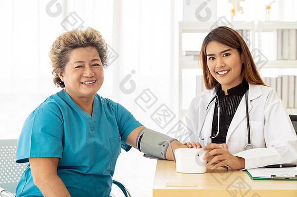 女医生测量血压力高级女人上了年纪的检查房间医院诊所