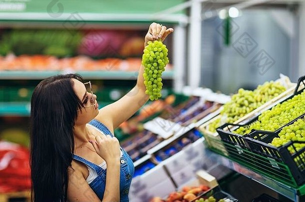 年轻的女孩选择葡萄超市