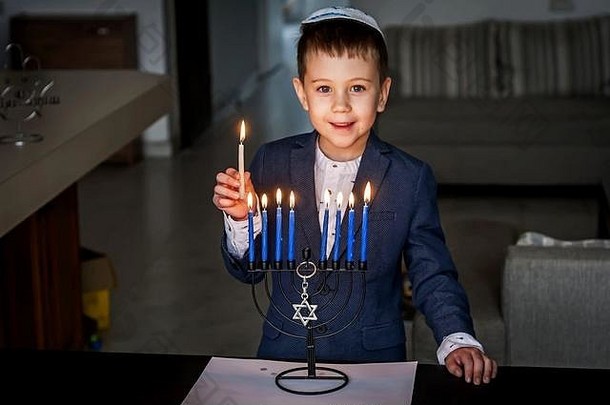 可爱的高加索人犹太人男孩照明蜡烛传统的光明节烛台枝状大烛台犹太人假期概念