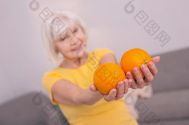 愉快的上了年纪的女人显示橙子