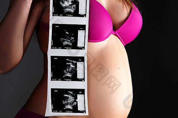 拍摄黑色的怀孕了女人持有孩子的超声波图片