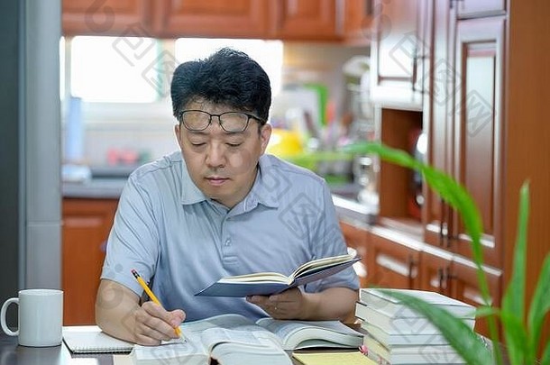 亚洲中年男人。坐着桌子上首页阅读书研究