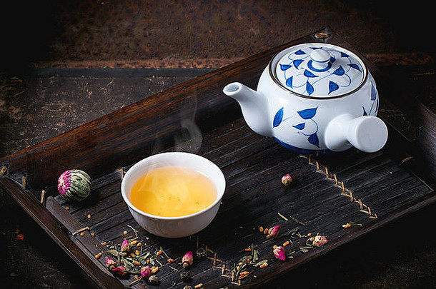 传统的日本茶壶杯绿色茶服务竹子托盘干茶变化黑暗背景