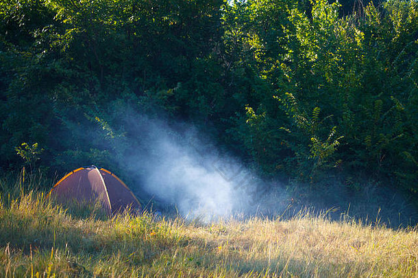 旅游帐篷吸烟篝火场前面森林日出Copyspace