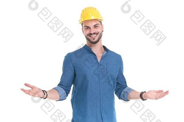 快乐的休闲男人。欢迎微笑穿蓝色的衬衫建设头盔站白色工作室背景