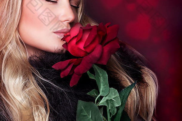 特写镜头肖像美丽的金发碧眼的女人关闭眼睛闻新鲜的红色的玫瑰背景心点缀
