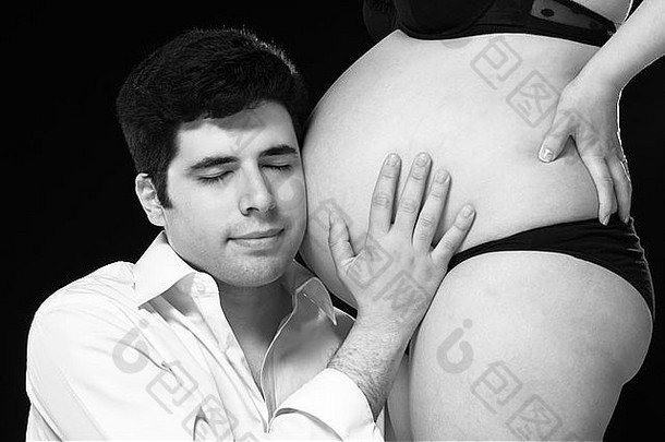 黑色的白色肖像年轻的父亲听婴儿肚子眼睛关闭