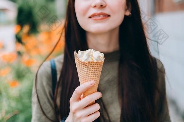 年轻的漂亮的女人吃冰奶油华夫格锥