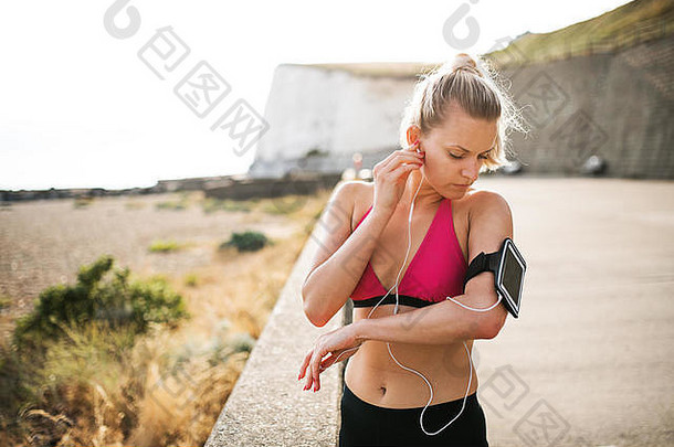 年轻的运动女人跑步者智能手机站海滩