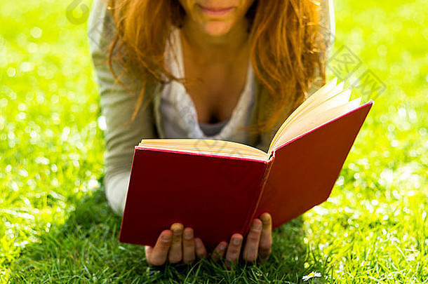 年轻的女人说谎草阳光明媚的一天阅读书