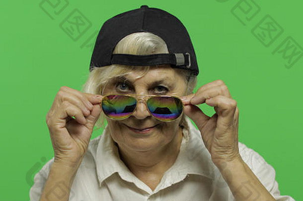 上了年纪的女人太阳镜帽微笑漂亮的快乐祖母白色衬衫的地方标志文本浓度关键绿色屏幕背景